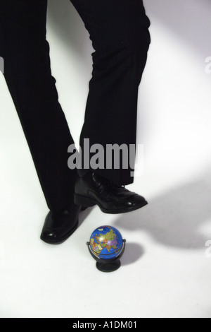 Beine Schuss eines Geschäftsmannes über Stempel auf einem minderwertigen Globus-Modell Stockfoto