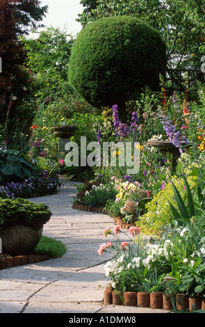 geschwungenen Steinpfad durch gut bepflanzten Garten Stockfoto