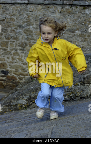 Kleines Mädchen läuft in die gepflasterte Straße Stockfoto