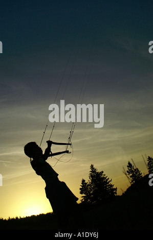 Ein kleines Kind Kind fliegen Parafoil Powerkite in Dämmerung Silhouette bunten Himmel im freien Abend Sommer Stockfoto