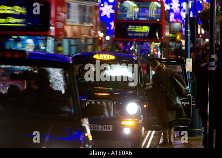 Ein schwarzes Taxi Taxi unter Weihnachtsbeleuchtung auf Regent Street London Vereinigtes Königreich Stockfoto