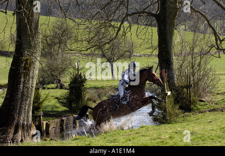 Junge Frau reitet ein Cleveland Bay kreuzen Thoroughbred Pferd im cross Country Eventing Konkurrenz Gloucestershire UK Stockfoto