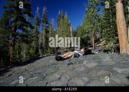 Ein junger Mann liegt auf Gletschern polierte Basaltsäulen Devils Postpile National Monument, Kalifornien, USA Stockfoto