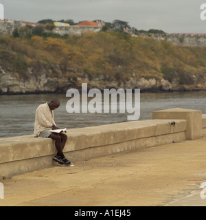 Mann sitzt auf einer Mauer, einem Buch Havanna Kuba Stockfoto