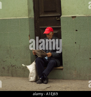 Mann sitzt in einem Hauseingang Zeitunglesen Havanna Kuba Stockfoto