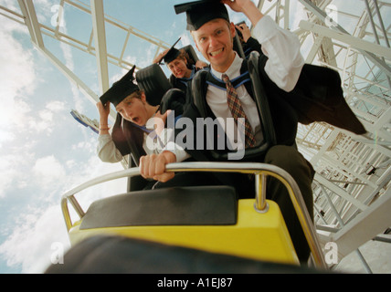 Achterbahnfahrt für männliche und weibliche Studenten in Kappen und Kleider zu feiern Stockfoto