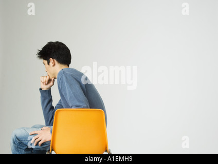Junger Mann sitzt auf dem Stuhl, halten Kinn