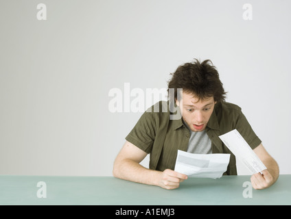 Junger Mann, Blick auf Brief, reagieren mit Überraschung Stockfoto