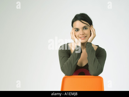 Junge Frau sitzt hinten am Stuhl, Lächeln Stockfoto