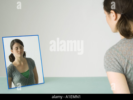 Junge Frau vor Spiegel mit Augen geschlossen Stockfoto