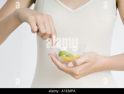 Junge Frau Holding Schüssel mit Zitronenschale und Kräutern Stockfoto