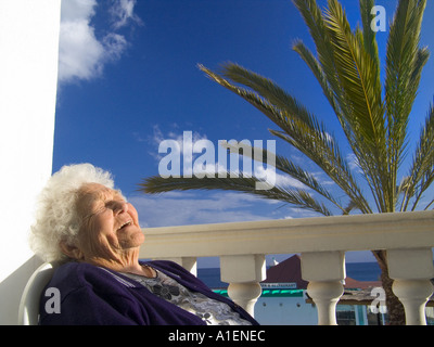 Ältere Frau 90 Jahre lächeln entspannt sich zufrieden in der Sonne in ihrem Urlaub Villa Haus mit Palmen Stockfoto