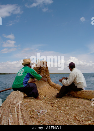 Lokale Uros Indianer Rudern eine traditionelle Reed Boot zwischen der Uros Inseln auf dem Titicacasee in Peru. Stockfoto