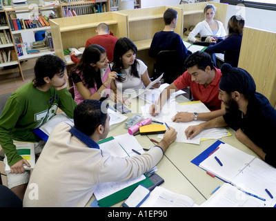 Multikulturelle Gruppe von Seniorenstudenten, die gemeinsam arbeiten und gemeinsam für ein Examensprojekt in der modernen Schulbibliothek austauschen Stockfoto