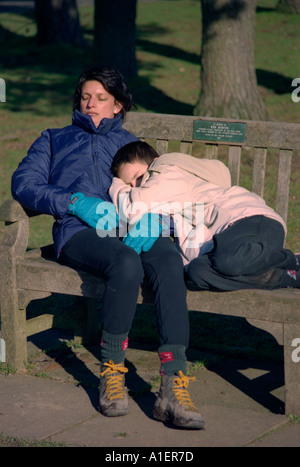 Mutter und Sohn schläft auf einer Bank. Stockfoto