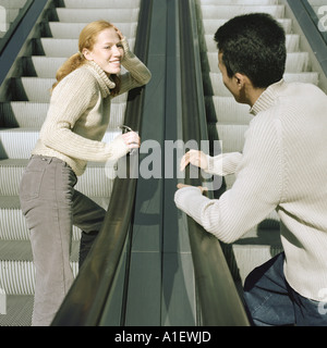 Junger Mann und junge Frau auf Rolltreppen Stockfoto