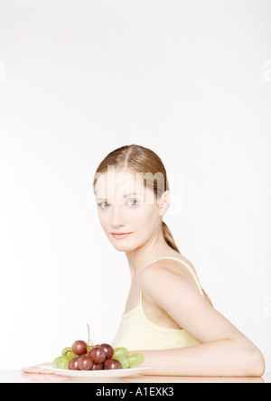 Woman sitting with plate of grapes Stockfoto
