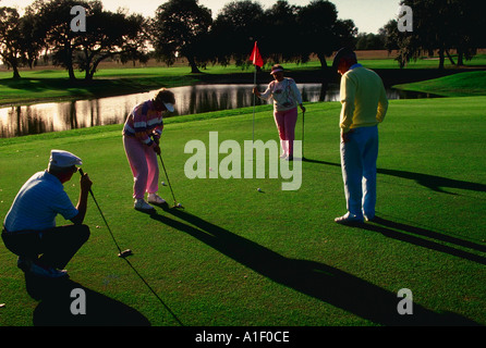 Zwei Paare im Ruhestand, Golfen auf Putting green Stockfoto