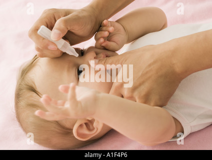 Eltern setzen fällt in Babys Augen, beschnitten, Ansicht Stockfoto