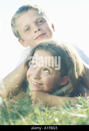 Jungen und Mädchen im Grass liegen Stockfoto