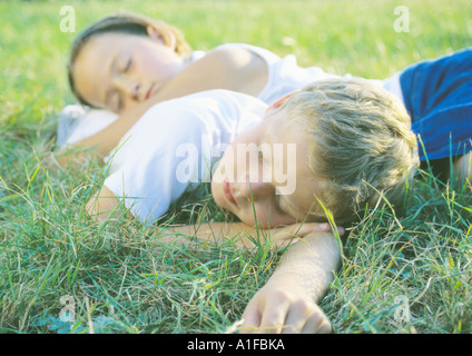 Jungen und Mädchen schlafen in Rasen Stockfoto