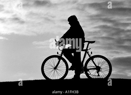 Boy am Pedal Fahrrad Silhouette gegen den Himmel in schwarz / weiß Stockfoto