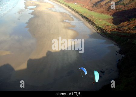 Luft-Luft-Schuss der Gleitschirme fliegen über dem Strand über Klippen von Rhossili Bucht Gower Halbinsel Wales UK Stockfoto