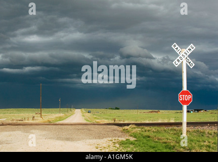 Dunkle Gewitterwolken über Feld mit Bahnübergang Colorado USA Stockfoto