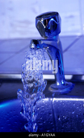 Reinigen Sie fließende Wasser aus Wasserhahn mit Wassertropfen in Küche Stockfoto