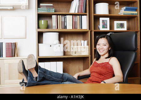 Porträt einer Geschäftsfrau, die mit ihren Beinen auf dem Tisch sitzen Stockfoto