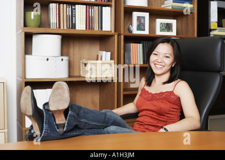 Porträt einer Geschäftsfrau, die mit ihren Beinen auf dem Tisch sitzen Stockfoto