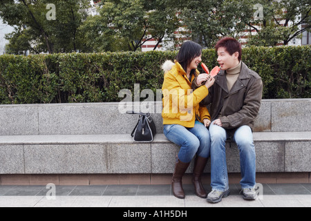 Junges Paar sitzt auf der Kante Wassermelone essen Stockfoto