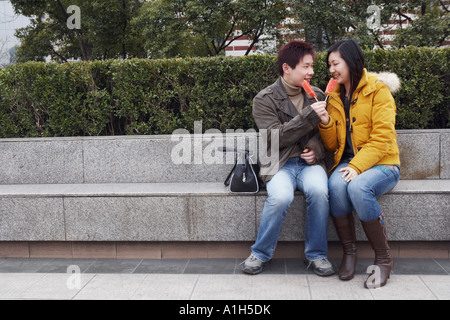 Junger Mann und eine junge Frau sitzt auf einem Felsvorsprung Wassermelone essen Stockfoto