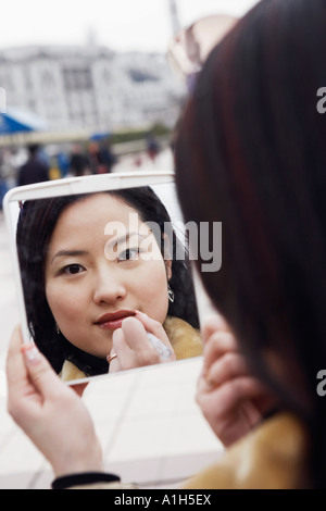 Nahaufnahme einer jungen Frau in einem Spiegel Auftragen von Lippenstift Stockfoto