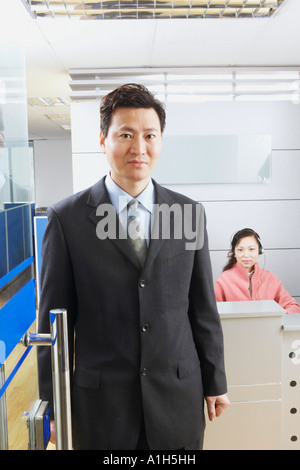 Porträt eines Kaufmanns im Büro mit Empfangsdame hinter ihm stehen Stockfoto