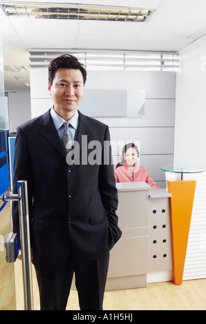 Porträt eines Geschäftsmannes stehend in einem Büro mit einer reifen Frau einen Kopfhörer tragen Stockfoto