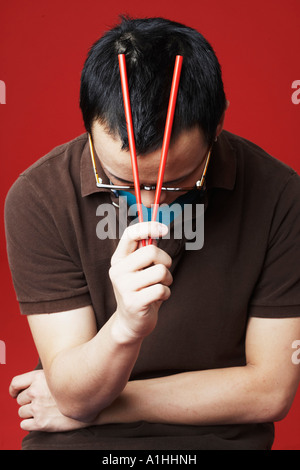 Nahaufnahme eines jungen Mannes mit Stäbchen auf dem Kopf Stockfoto