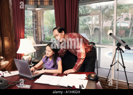 Mädchen mit einem Laptop mit ihrem Großvater neben ihr Stand Stockfoto