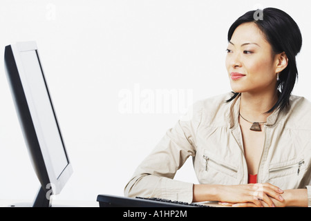 Eine Geschäftsfrau, die lächelnd in der Nähe von einem Computer in Nahaufnahme Stockfoto