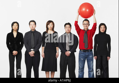 Porträt eines jungen Mannes stehend mit einem Ball mit einer Gruppe von Führungskräften der Wirtschaft Stockfoto