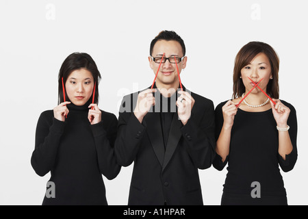 Zwei junge Frauen und ein junger Mann, gestikulieren sprechen nichts Böses, nichts Böses hören, sehen, nichts Böses mit Stäbchen Stockfoto