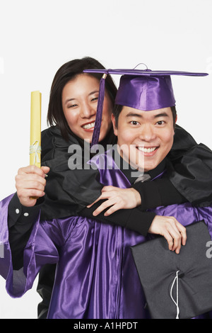 Porträt einer jungen Frau Reiten Huckepack auf männliche Absolvent Stockfoto
