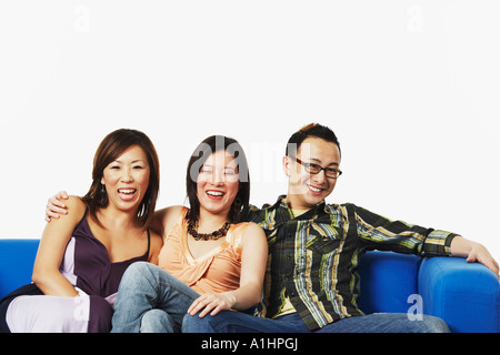 Zwei junge Frauen und ein junger Mann sitzt auf einer couch Stockfoto