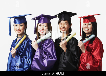 Porträt von vier weiblichen Absolventen in einer Reihe hält Diplome Stockfoto