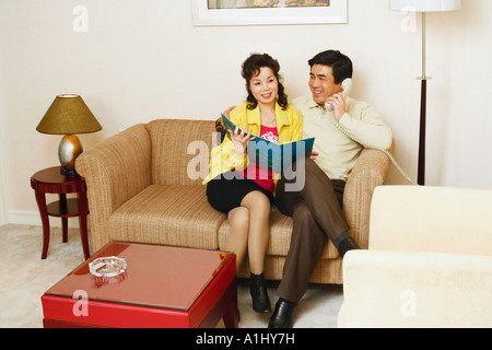 Reifer Mann sitzt auf einer Couch mit einer reifen Frau am Telefon sprechen Stockfoto