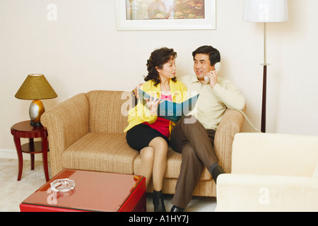 Reifer Mann sitzt auf einer Couch mit einer reifen Frau am Telefon sprechen Stockfoto