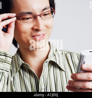 Nahaufnahme eines Mitte erwachsenen Mannes hält ein Mobiltelefon und einen Stift Stockfoto