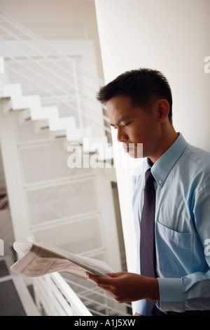 Seitenansicht eines Geschäftsmannes an eine Wand gelehnt und Zeitung lesen Stockfoto