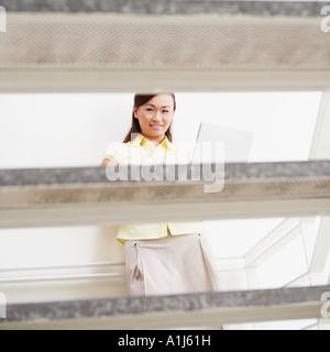 Porträt einer jungen Frau an eine Wand gelehnt und mit einem laptop Stockfoto