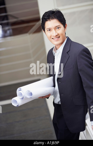 Porträt eines Geschäftsmannes auf einer Treppe stehen und halten Blaupausen Stockfoto